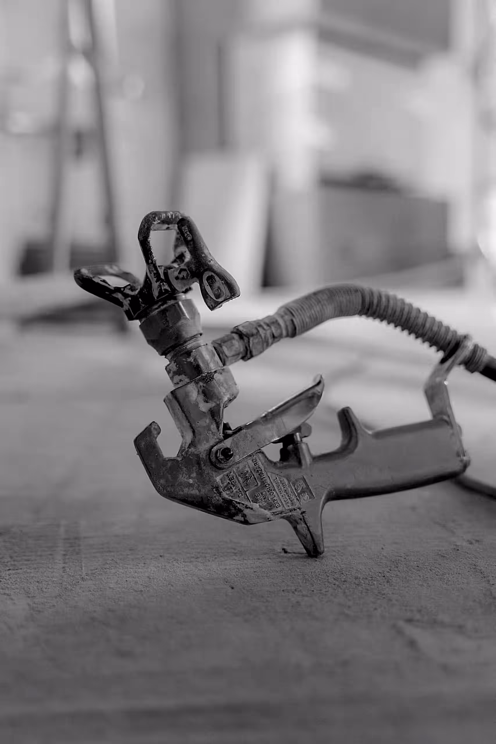 Monochrome close-up of a spray gun on a blurred background. Industrial focus.